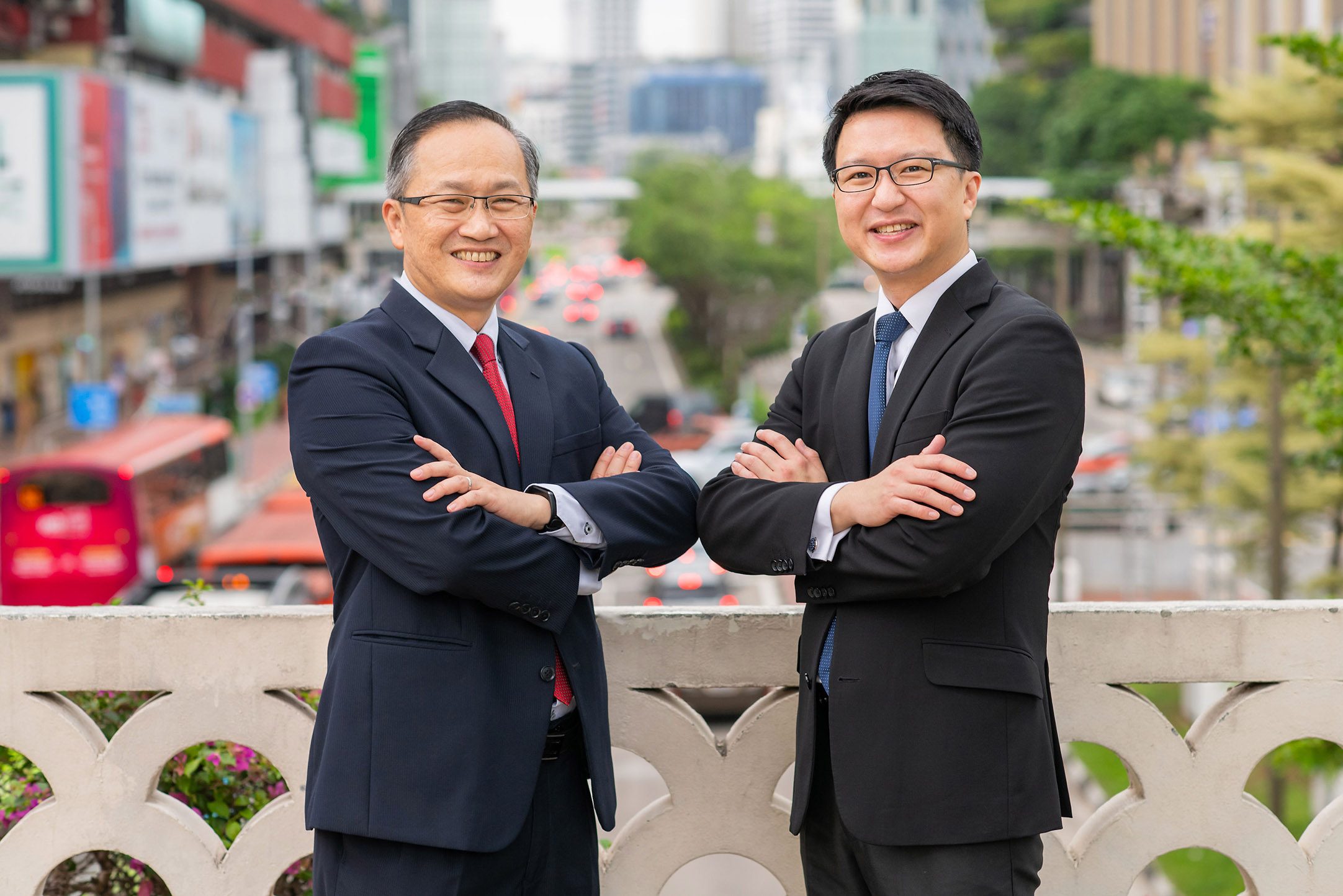 Lim Biow Chuan and Lau Kah Hee, the founders of BC Lim & Lau LLC, standing with arms folded on a bridge above New Bridge Road